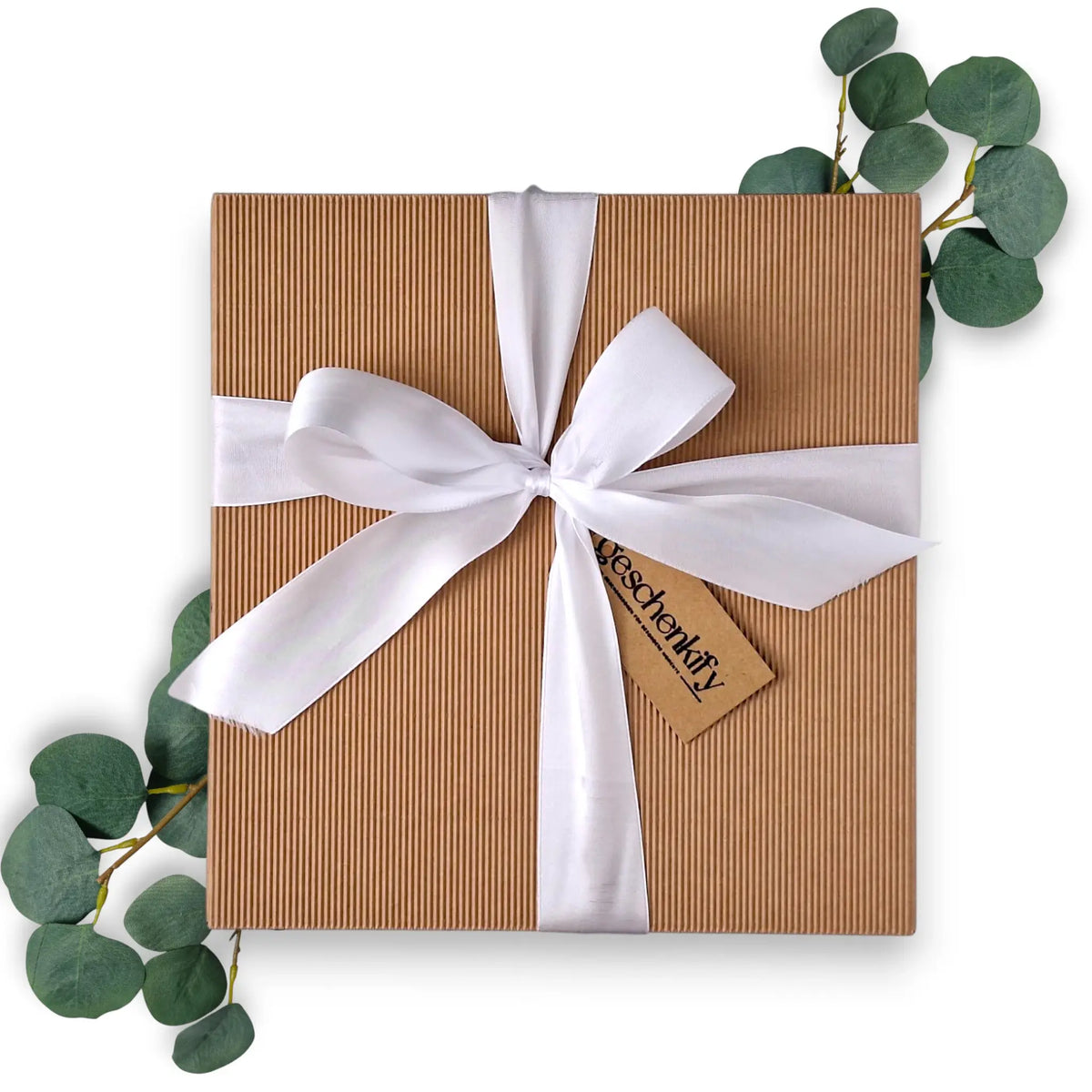Hochwertige, geschlossene Geschenkbox aus geriffeltem braunem Naturkarton, elegant gebunden mit einer weißen Satinschleife und einem geschenkify-Anhänger.